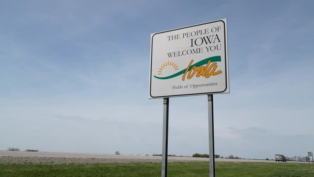 Iowa welcome roadside sign against blue sky at state border with Missouri,  travel concept