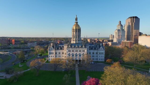Aerial drone video zooming out from the state capitol building in Hartford, Connecticut in evening at sunset