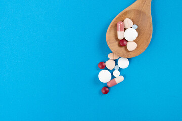 many colorful drug medicines or pill in a spoon on blue table background, healthy and medicine...