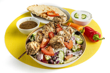 Greek chicken souvlaki on a plate of Greek salad