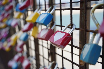 Colorful padlocks in the shape of heart on the fence.