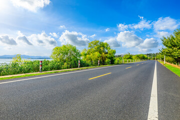 Asphalt highway road and green trees landscape by the lake
