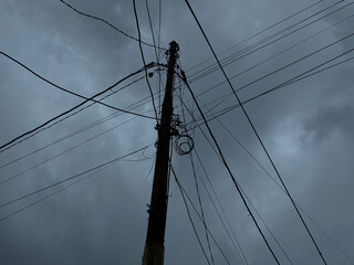 Power supply pole and cables, with dark cloudy sky background