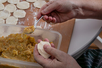 On the wooden counter top Woman hands are making a damp dumpling