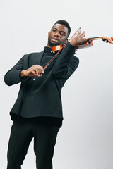 Elegant musician in formal attire playing the violin against a plain white backdrop, artistic...