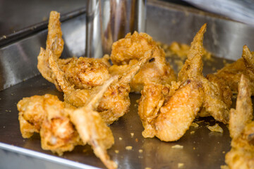 a street food stall where freshly prepared fried chicken wings are on display