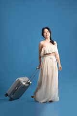 Portrait of asian girl posing on blue background, traveling in summer