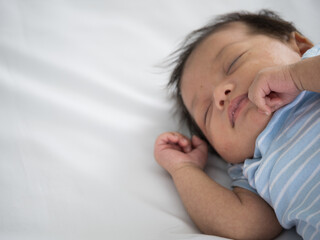 Portrait of three weeks Australian Asian newborn baby or infant lying on the white bed and close her eyes..
