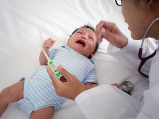 Baby illness medicine flu fever and thermometer, a doctor checks the temperature of the ill baby. Digital thermometer to measure the heat temperature of a sick child. Baby fever concept.