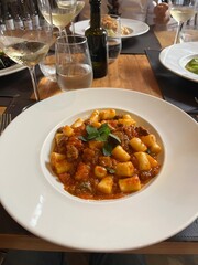 Plate of gnocchi served with a glass of white wine at an Italian restaurant. The delicious pasta dish is complemented by the elegance of the wine, creating a perfect dining experience