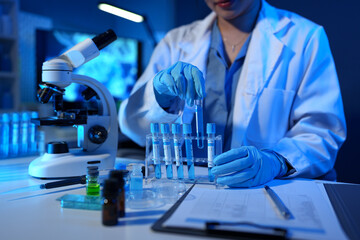 Scientists use scientific test tubes with records of chemicals or drugs being tested and examined under a microscope in a science laboratory for biology, biotechnology, medicine.
