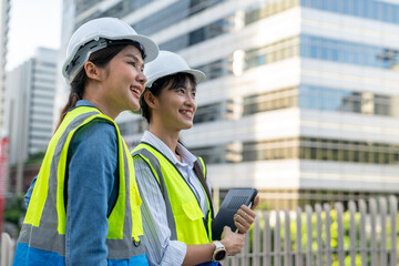 Two Asian confident engineer woman working together with a cityscape in the background