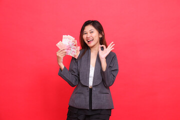 The expression of a happy Asian office woman holding a credit, debit card and money while signing...