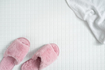 Fluffy pink slippers on the tiled bathroom.