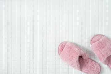 Fluffy pink slippers on the tiled bathroom.