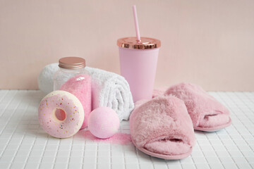 Fluffy pink slippers, bombs and bath salts on the tiled bathroom floor.