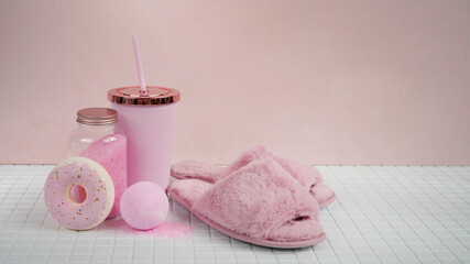 Fluffy pink slippers, bombs and bath salts on the tiled bathroom floor.