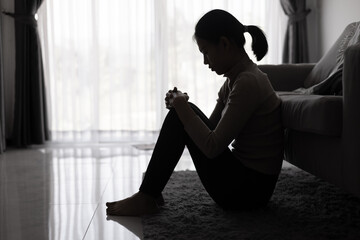 Depressed woman, Silhouette of teenager girl with depression sitting alone  in the dark room. Black and white photo.