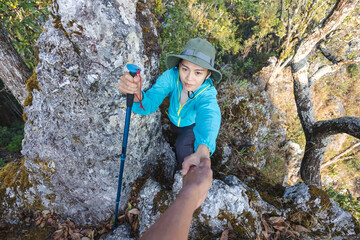 Person women hikers climbing up mountain cliff and one of them giving helping hand. People success,...