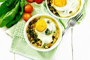 Scrambled eggs with spinach in bowl on board top