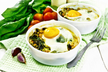 Scrambled eggs with spinach in bowl on board