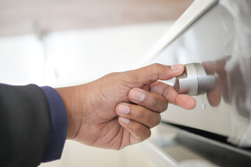 Close up of men hand setting temperature control on oven.