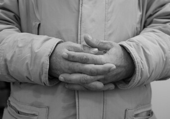 Close up of old man's crossed hands resting on stomach. black and white photo