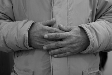 Close up of old man's crossed hands resting on stomach. black and white photo