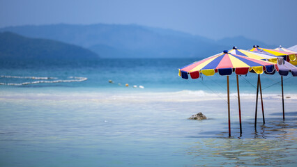 Umbrellas beach in the blue sea on sunny day, Beach umbrella on sandy coast in sea.