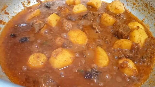 Traditional potato and beef korma boiling, ready to be served, closeup. Pakistani and Indian spicy food cooking