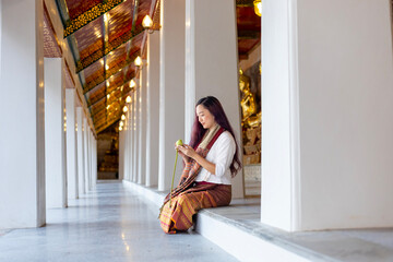 Buddhist asian woman in traditional cloth is folding lotus leaf in Buddhist temple as meditation...