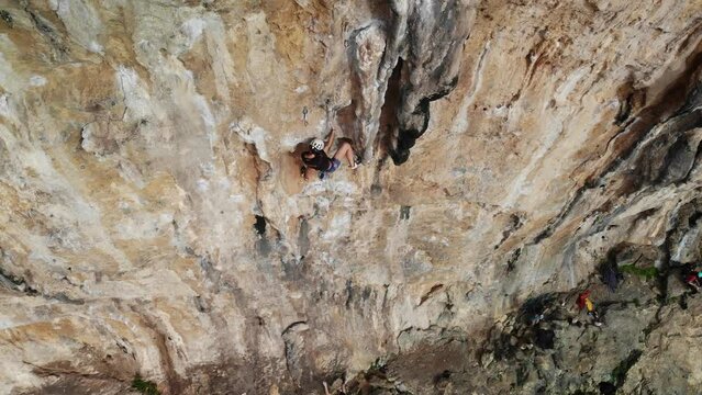 Aerial drone view of strong female climber climbing a difficult sport climb route in a steep wall at Kalymnos island, Greece. High quality 4k footage.