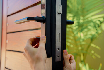 A technician installs a modern smart door lock on the wood door