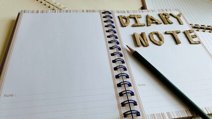 Notebook, diary, paper, pencil, brown, black and white on the table.