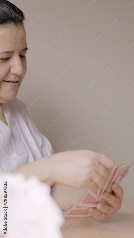 Wall mural Female caregiver playing cards in a geriatric