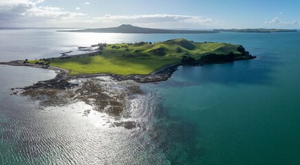 The volcano and crater of Browns Island in the Waitamata Harbour. In the background is Rangitoto Island. Auckland, Auckland, New Zealand. - obrazy, fototapety, plakaty