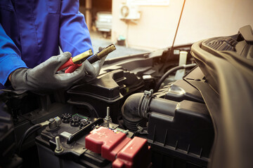 Auto mechanic holding connect jumper cable or car booster cables on terminal dead battery for...