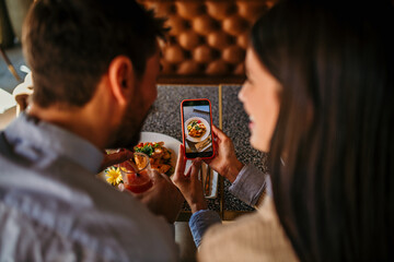 Couple photographing food for a social media in the restaurant