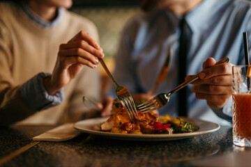 Hand close-up of couple sharing and eating lunch in a restaurant