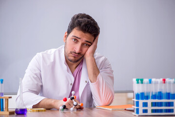 Young male chemistry teacher sitting in the classroom