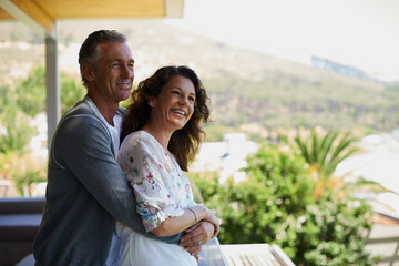 Obraz premium Home, balcony or mature couple hug on anniversary for support, date or love for care, marriage or trust. Smile, view or happy woman bonding with man in retirement, honeymoon break or house to relax