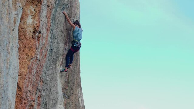 rock climbing and mountaineering. A girl climbs a rock. A strong athlete overcomes a difficult climbing route. Extreme hobby. A woman plays sports in nature.

