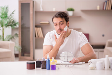 Young man shaving face at home