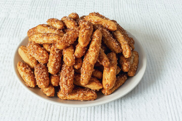 Delicious crispy sugar and cinnamon cookies on plate and fabric tablecloth