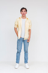Full body photo of a handsome young asian man in an unbuttoned yellow polo and white shirt and blue...
