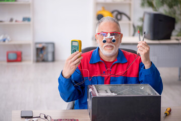 Old male repairman repairing computer