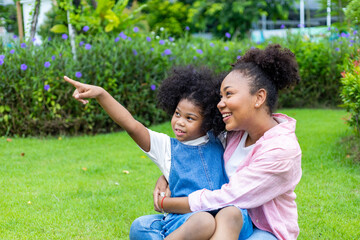 African American mother is playing piggyback riding with her young daughter while having a summer...