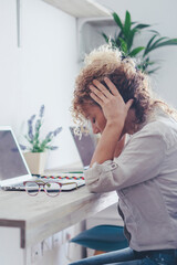 Unwell young Caucasian woman work on computer at home office take off glasses suffer from migraine...