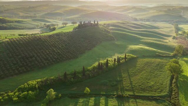 Classic Tuscany landscape with green hills and farmland country at sunrise. Aerial shot of green spring fields and hills in Tuscany, Italy