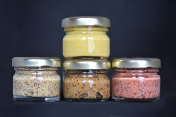 Four small jars with different mustard